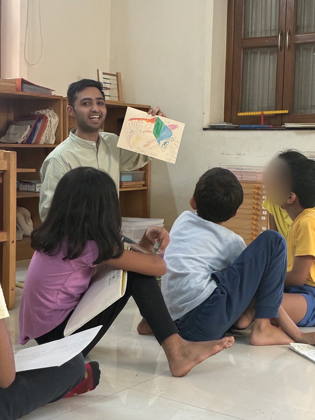 An educator holds up a child's drawing for older children