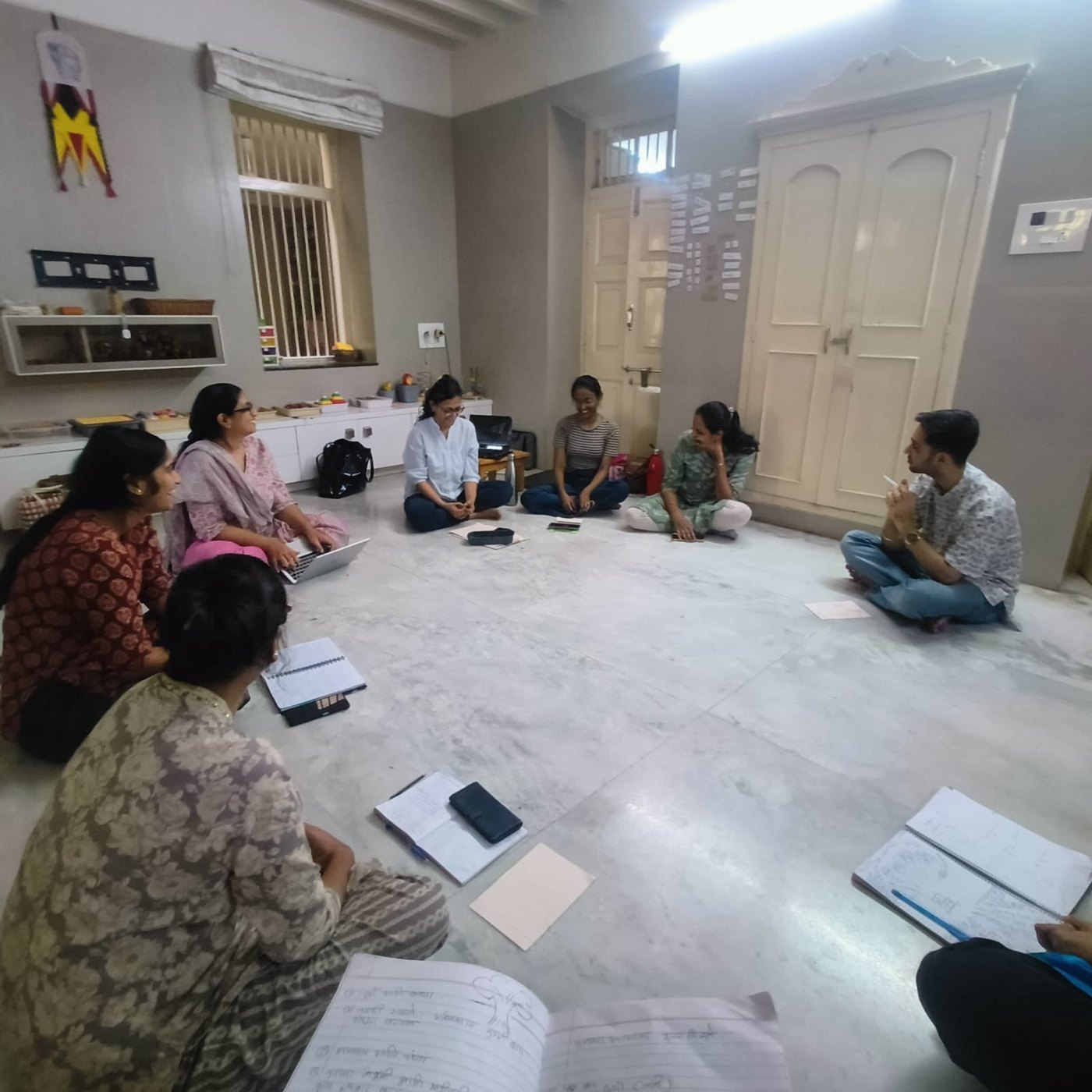 Our educators sit in a circle on the floor with their notebooks